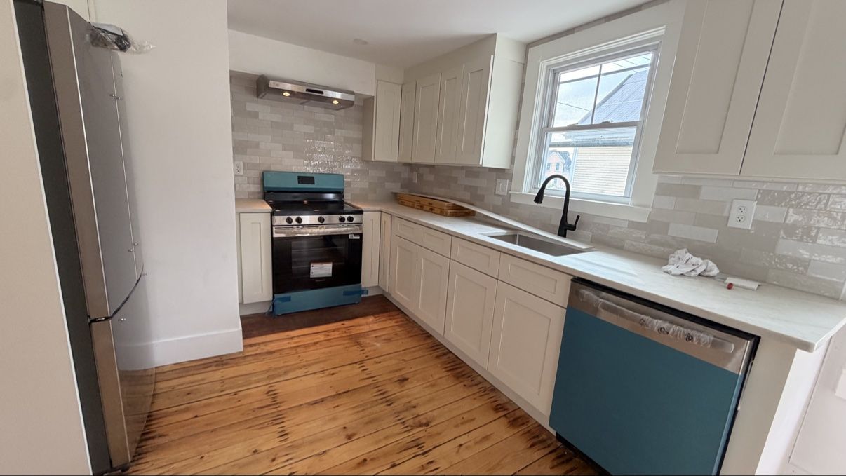 Finished galley kitchen with white cabinets and pine floors