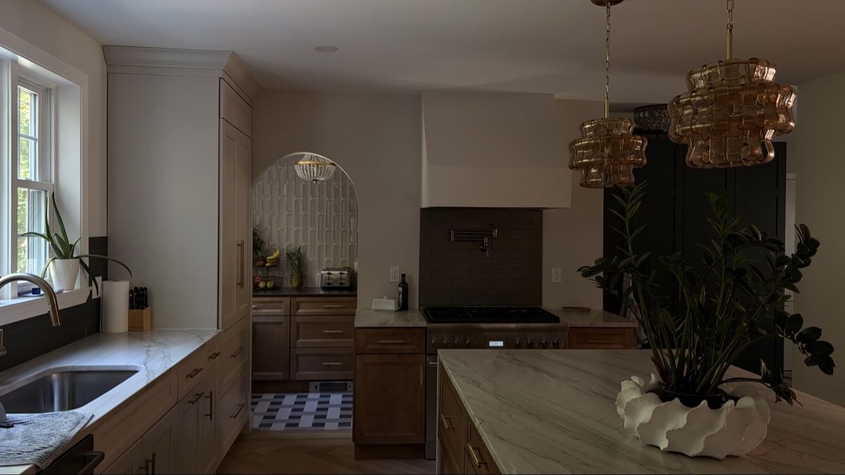 Finished kitchen with marble island, woven pendants, and arched pantry opening