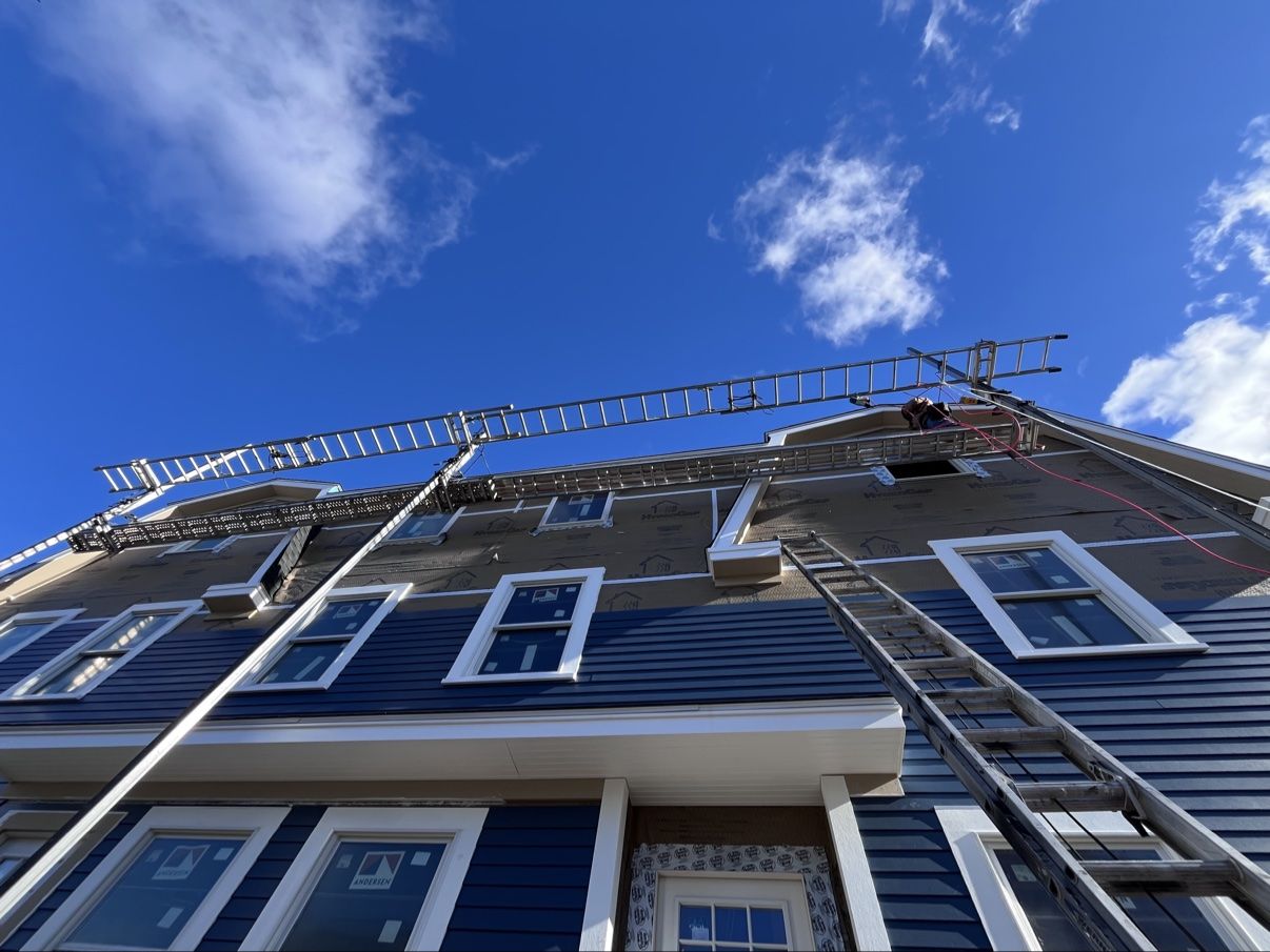 Ladders and staging against the finished blue siding